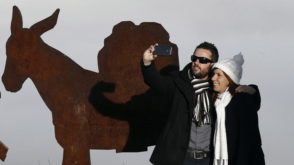 Una pareja se toma una fotografía junto a una de la figuras del Camino de Santiago situadas en la sierra del Perdón. EFE/Jesús Diges