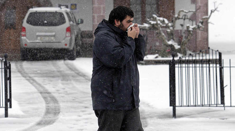 Un señor camina por la calle, afectado por la gripe y sonándose los mocos, durante el temporal de nieve que azota al Norte de Navarra. EFE/Iban Aguinaga