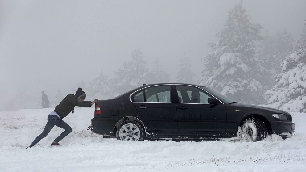 Una persona empuja un coche que ha quedado atrapado en la nieve en el Alto de El Perdón en Navarra, comunidad donde la Agencia Estatal de Meteorología mantiene el aviso naranja por nevadas. EFE/Villar López