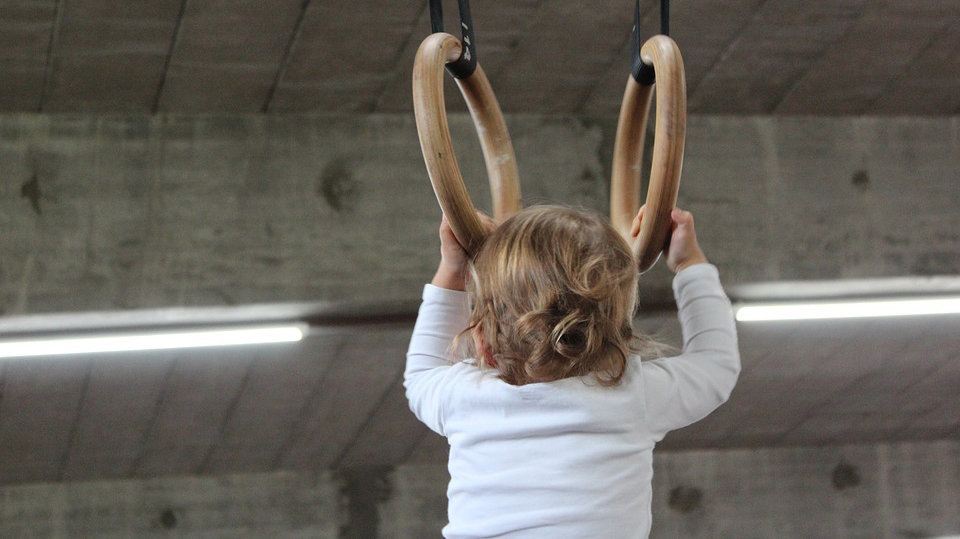 Imagen de un niño pequeño durante una clase de gimnasia practicando un ejercicio sobre aros ARCHIVO