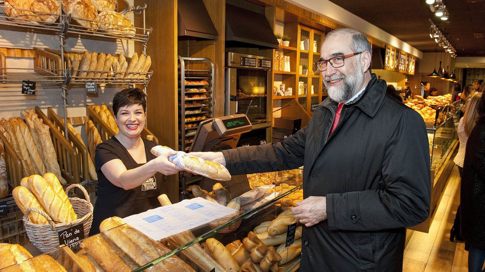 El consejero de Salud, Fernando Domínguez, adquiere una barra de pan en una panadería de Pamplona que se ha sumado a la campaña de prevención del cáncer de colon.