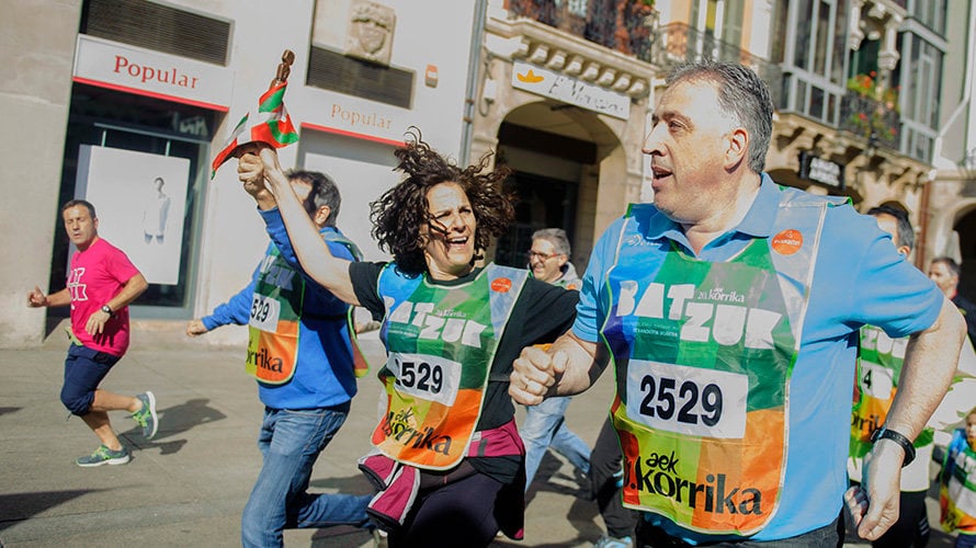 Itziar Gómez (Geroa Bai-PNV) y el alcalde Joseba Asirón (Bildu) corren con la ikurriña durante la Korrika en Pamplona