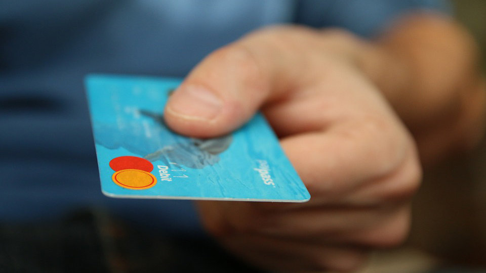 Un hombre sacando dinero con una tarjeta de crédito.