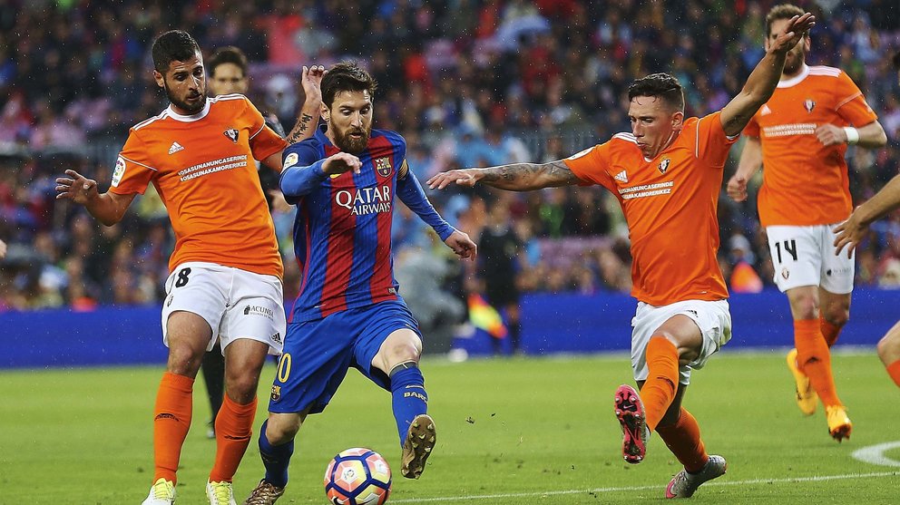El delantero argentino del FC Barcelona Leo Messi (c) se deshace de los centrocampistas Fran Mérida (i) y Jaime Romero (d), de Osasuna, en el Camp Nou. EFE/Alejandro García