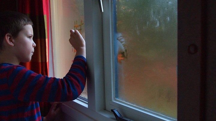 Imagen de un menor dibujando sobre el vaho de una ventana empañada ARCHIVO