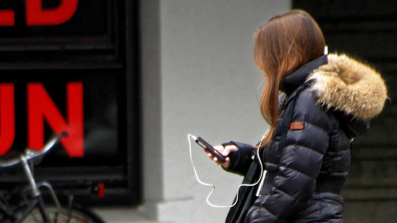 Imagen de una chica escuchando música a través de los cascos de su teléfono móvil ARCHIVO