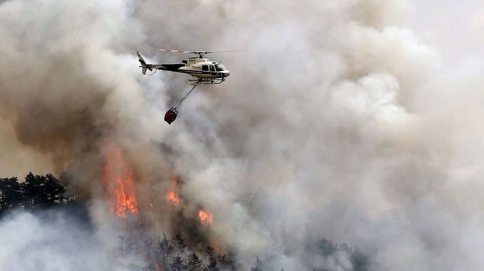Un helicóptero lanza agua sobre el pinar de Arazuri donde esta tarde se ha iniciado un incendio forestal hasta donde se han desplazado efectivos que trabajan en su extinción. EFE/Jesús Diges