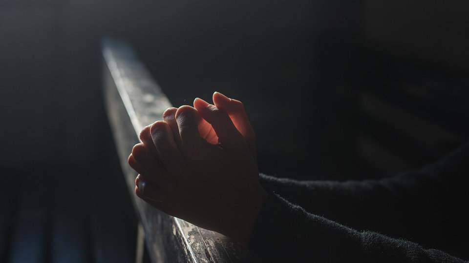 Una persona rezando en el banco de una iglesia ARCHIVO