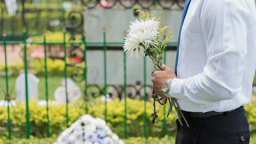Un hombre porta un ramo de flores en un cementerio