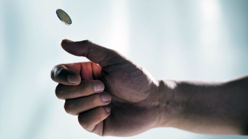 Una persona lanza una moneda al aire.