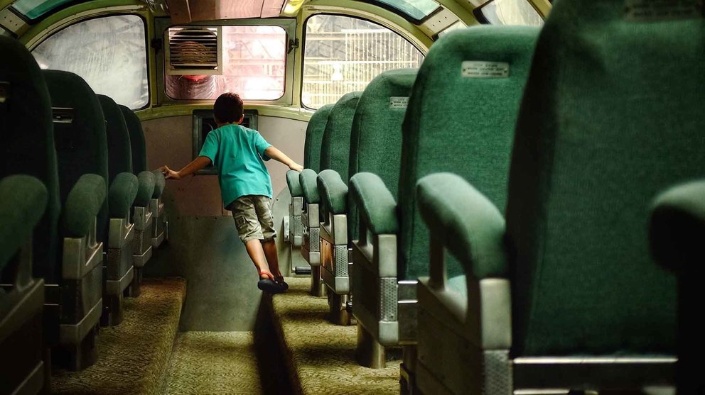 Un niño camina entre los asientos de un vagón de tren