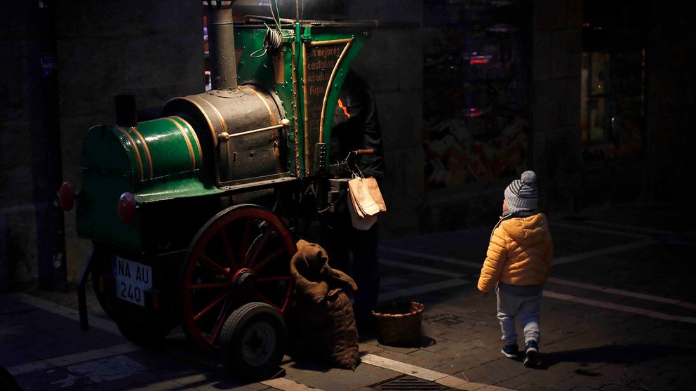 Un niño se acerca a comprar un cucurucho de castañas en uno de los tradicionales puestos de Pamplona en un día marcado por un tiempo frío. EFE/Villar López