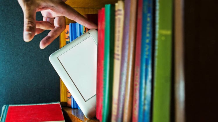 Un ebook en una estantería junto a varios libros en papel ARCHIVO