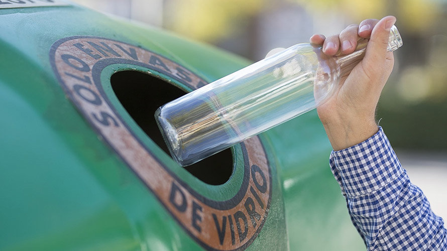 Una persona recicla una botella de vidrio