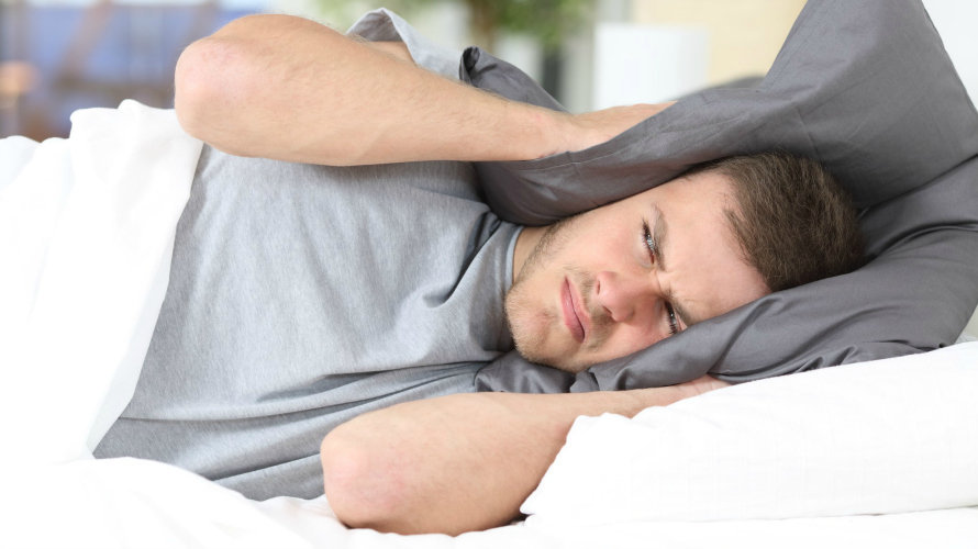 Un hombre trata de conciliar el sueño tapándose la cabeza con una almohada por el fuerte ruido ARCHIVO
