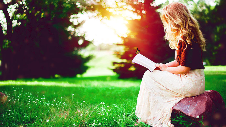 Una chica lee un libro en un parque.