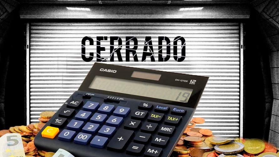 Un negocio con la persiana bajada y una calculadora con varias monedas