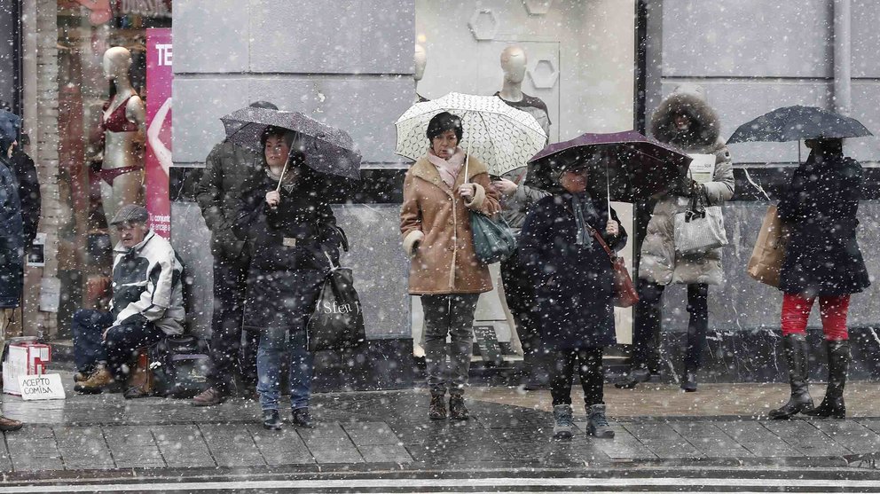 Varias personas pasean por las tiendas de Pamplona, en una jornada con tiempo frío y marcado por la nieve. EFE/Jesús Diges