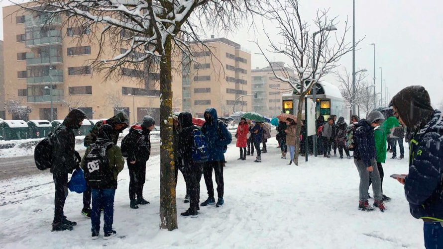 Varios estudiantes aguardan en la parada la llegada del autobús escolar en Sarriguren. CEDIDA