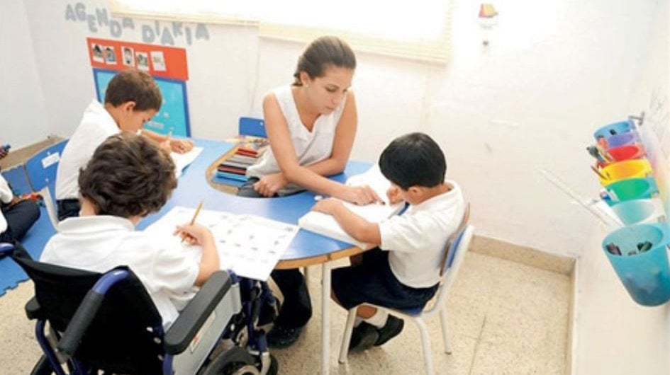 Una profesora atiende a niños con necesidades educativas específicas durante una clase en un colegio ARCHIVO
