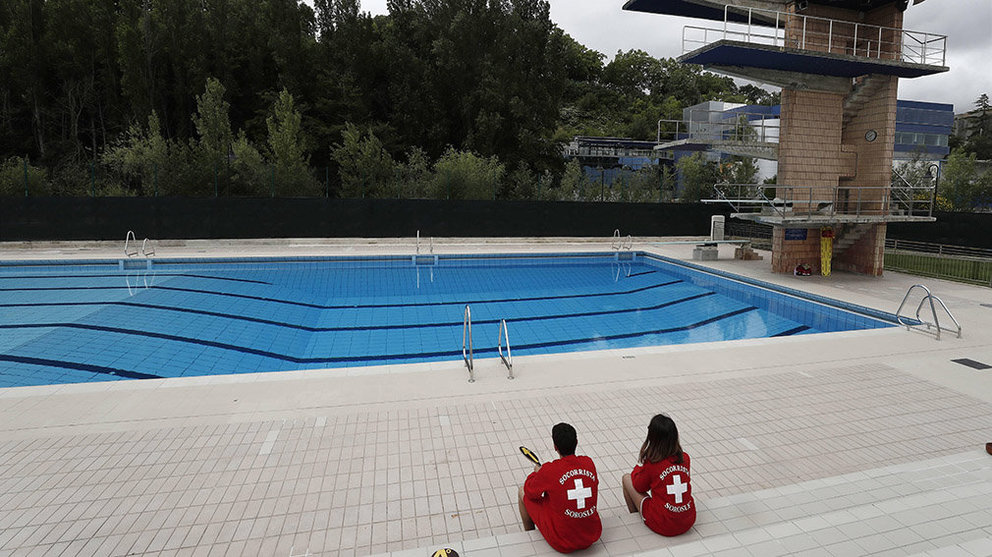 Dos socorristas trabajan en una piscina de Pamplona sin bañistas durante un día de verano marcado por el tiempo desapacible, el cielo nuboso y la posibilidad de lluvia. EFE/Jesús Diges