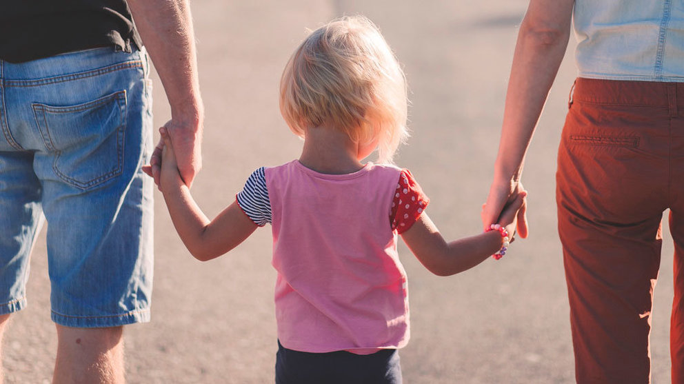 Una niña pasea de la mano con sus padres. ARCHIVO