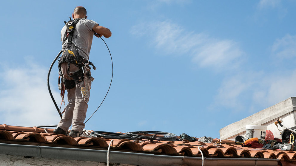 Un operario trabaja en la instalación del cable de fibra óptica en un tejado de Pamplona (05). IÑIGO ALZUGARAY