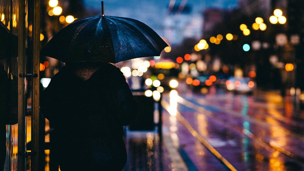 Una persona caminando de noche bajo la lluvia por las calles de una ciudad