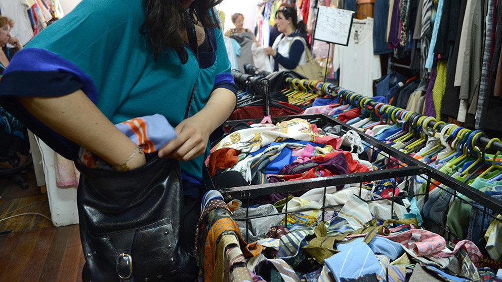 Imagen de una joven robando ropa de una tienda mientras una dependienta atiende a otros clientes ARCHIVO