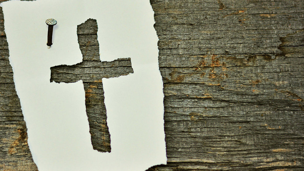 Una cruz sobre un papel como símbolo de una despedida.
