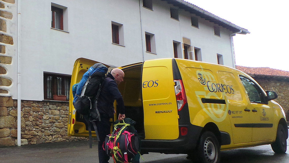 Un empleado de Correos entrega en un albergue del camino de Santiago a su paso por Navarra las mochilas transportadas con el servicio dirigido a peregrinos CORREOS