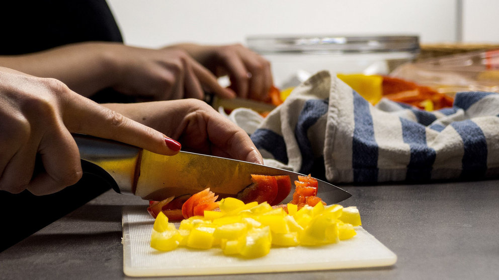 Mujer cortando alimentos en una cocina ARCHIVO