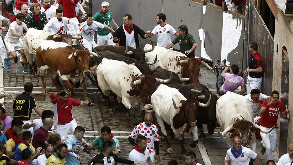 Los toros de la ganadería de Jandilla a su paso por la curva de Mercaderes durante el cuarto encierro de los Sanfermines 2019. EFE/Jesús Diges