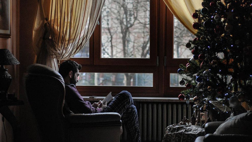 Un hombre leyendo en un sillón junto a un árbol de Navidad ARCHIVO