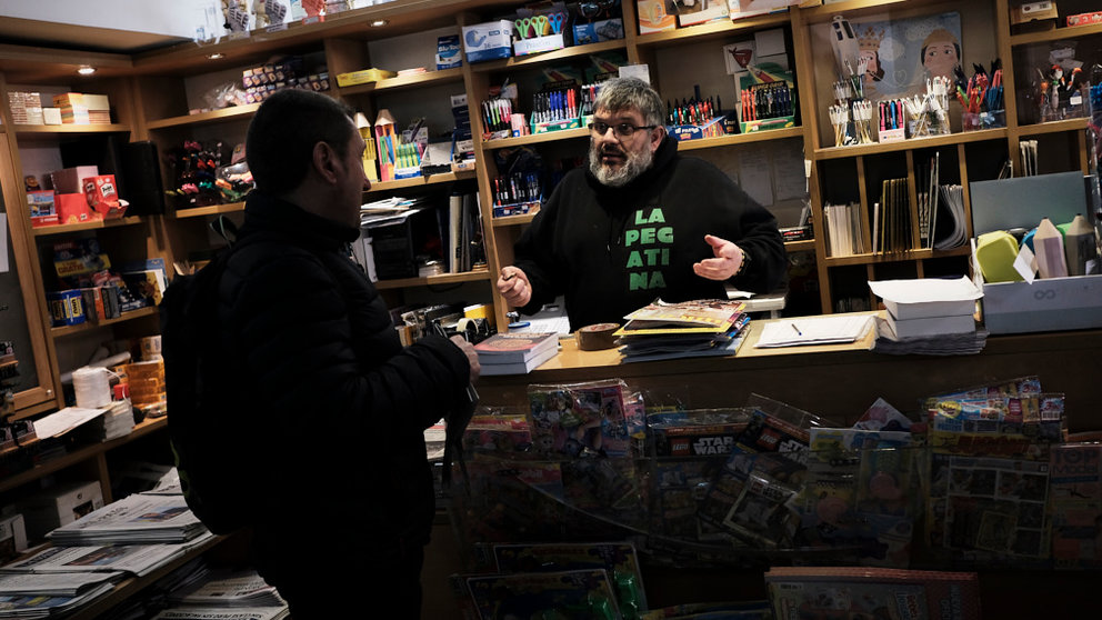Carmelo Buttini, comerciante del Casco Viejo de Pamplona, habla con un cliente en su tienda de prensa. PABLO LASAOSA