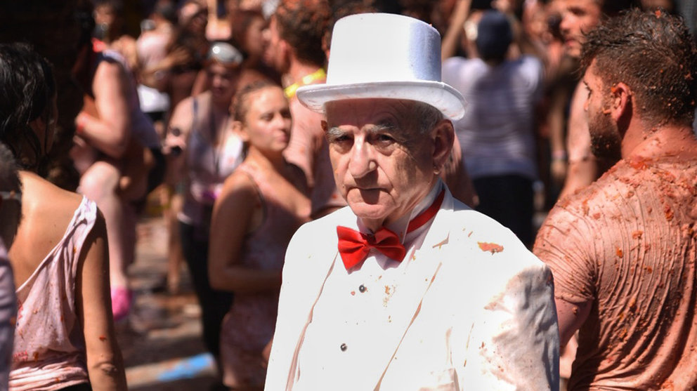 Un hombre vestido con un traje y un sombrero blanco, pasea por una calle de Buñol, durante la fiesta de la Tomatina de Buñol 2019. Europa Press.