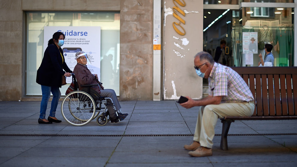 Una mujer con mascarilla empuja a un hombre en silla de ruedas durante la crisis del coronavirus. MIGUEL OSÉS
