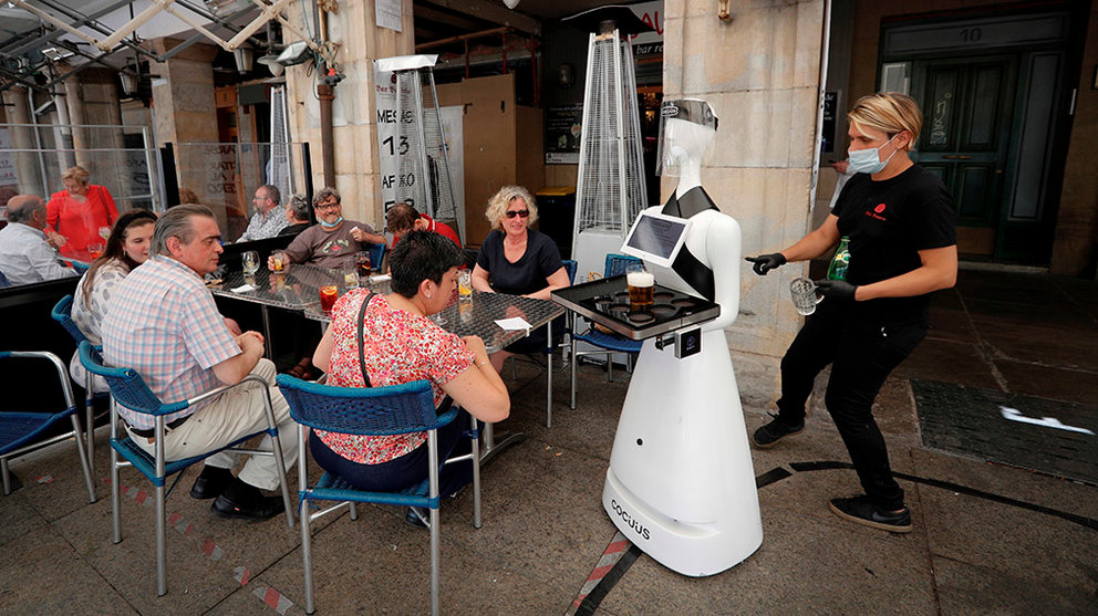 El robot Alexia sirve una consumición a unos clientes en la terraza del Bar Baviera de Pamplona. EFE/Villar Lopez