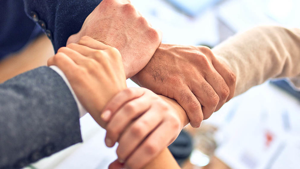 Varias personas unen sus manos en una reunión de trabajo. ARCHIVO