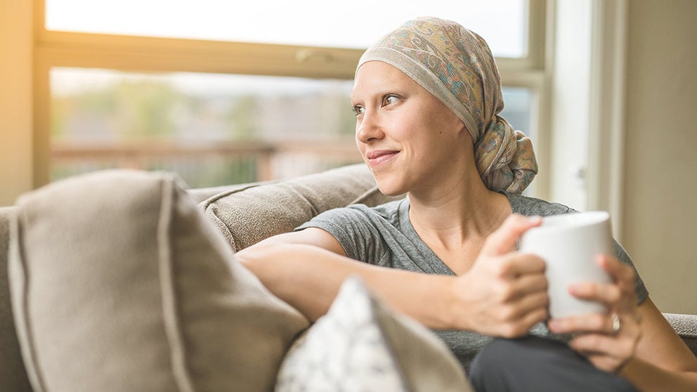Ethnic young adult female cancer patient sipping tea while at home