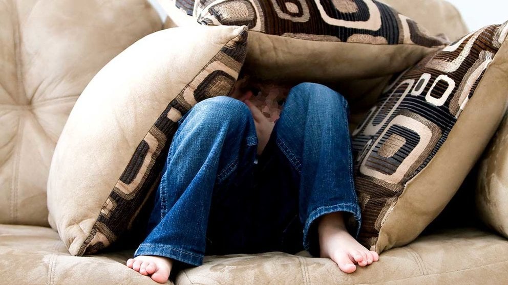 Una niña se esconde atemorizada entre los cojines de un sofá. ARCHIVO