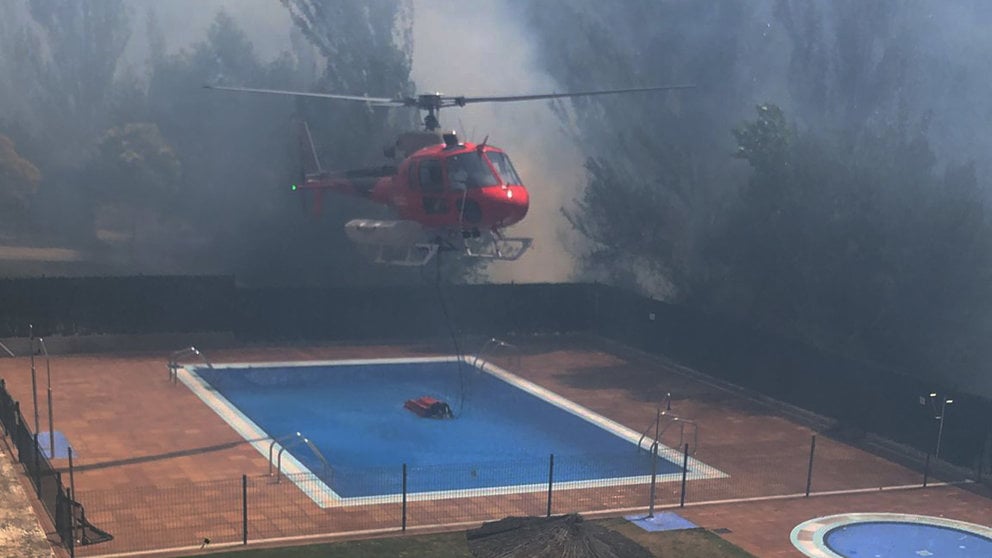 Un helicóptero recoge agua de una piscina para sofocar un incendio cerca de viviendas en Olloqui. CEDIDA