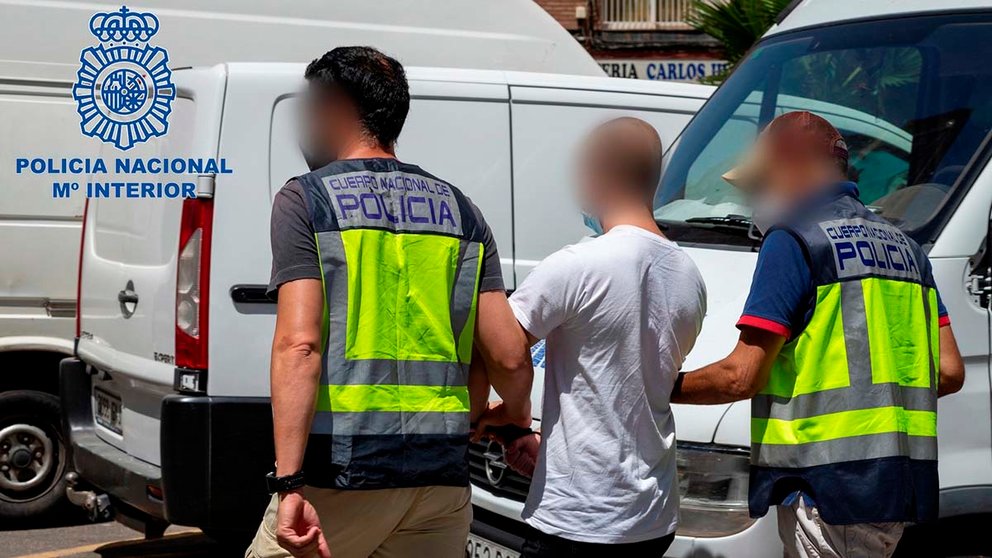 Dos policías escoltan a un joven de 20 años tras su detención en Cartagena como presunto autor del ataque con artefactos incendiarios a la sede de Podemos en esta ciudad el pasado 2 de abril. EFE/ Policía Nacional