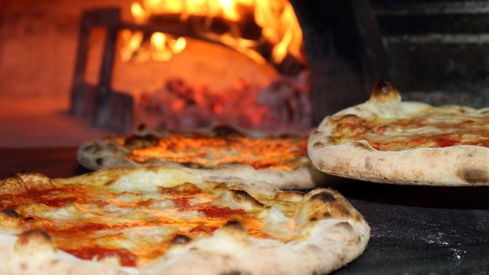 Varias pizzas haciéndose en un horno artesanal de leña ARCHIVO