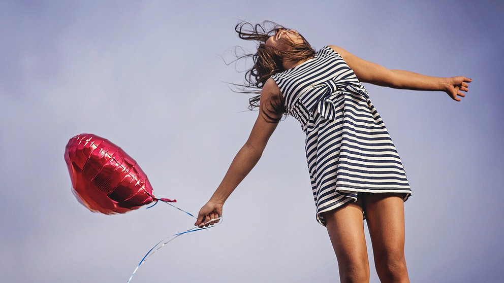 Imagen de una niña con un globo saltando de alegría. ARCHIVO