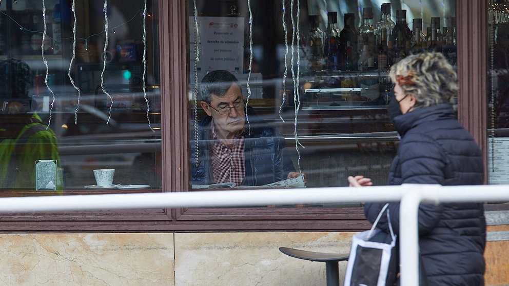 Una persona lee un periódico mientras toma un café en el interior de un bar en Pamplona tras la recuperación de la obligatoriedad del uso de las mascarillas en exteriores. IÑIGO ALZUGARAY