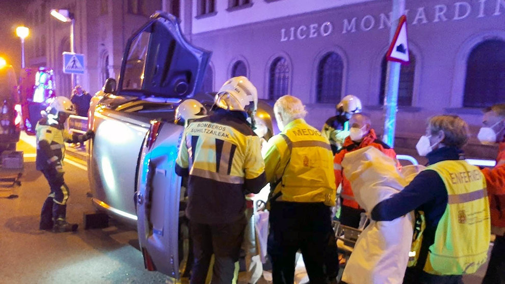 Los bomberos de Navarra trabajan junto al vehículo accidentado en la calle Aoiz, a las puertas del colegio Líceo Monjardín. BOMBEROS DE NAVARRA
