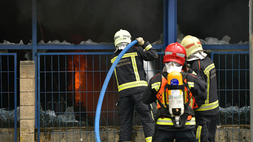 Los bomberos extinguen las llamas en el bazar chino Hiper Sol de Burlada, que ha ardido por completo en un incendio. PABLO LASAOSA