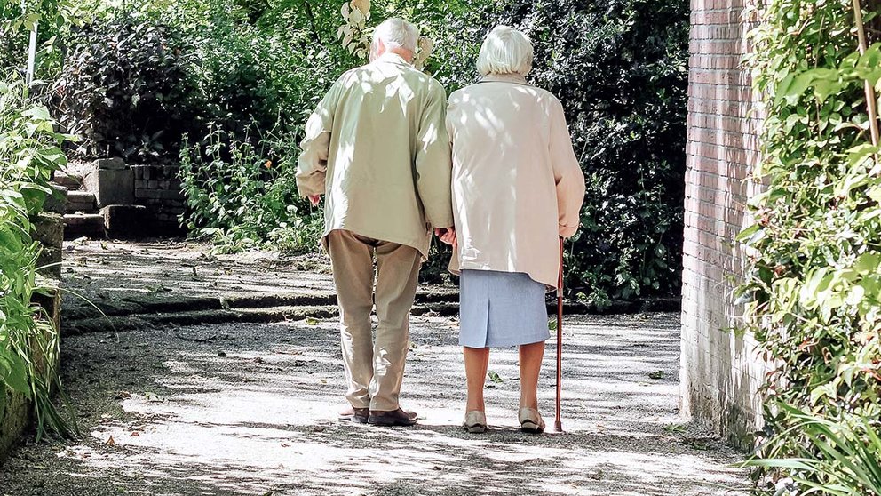 Dos personas mayores caminan por la calle. ARCHIVO