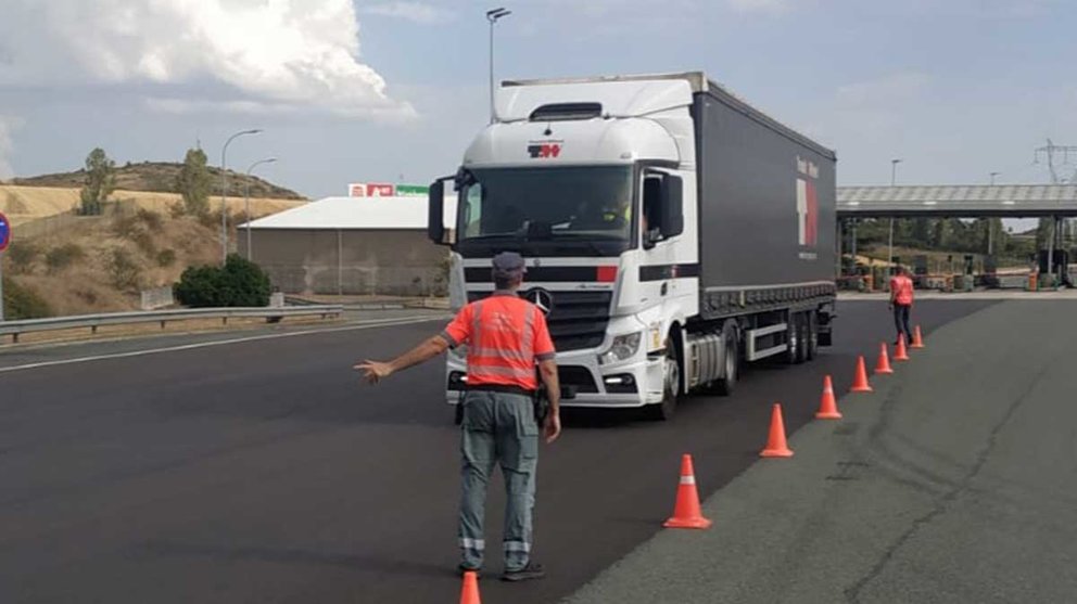 Un agente de la Policía Foral detiene un camión en la AP-15 para informarle del cierre de la frontera de Francia para vehículos pesados. POLICÍA FORAL.